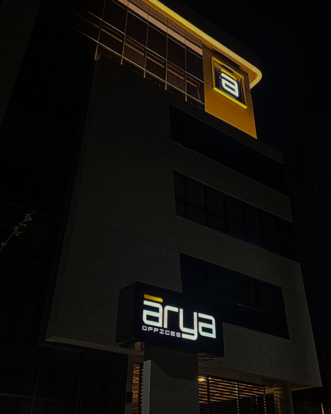 Fachada iluminada do Arya Offices à noite